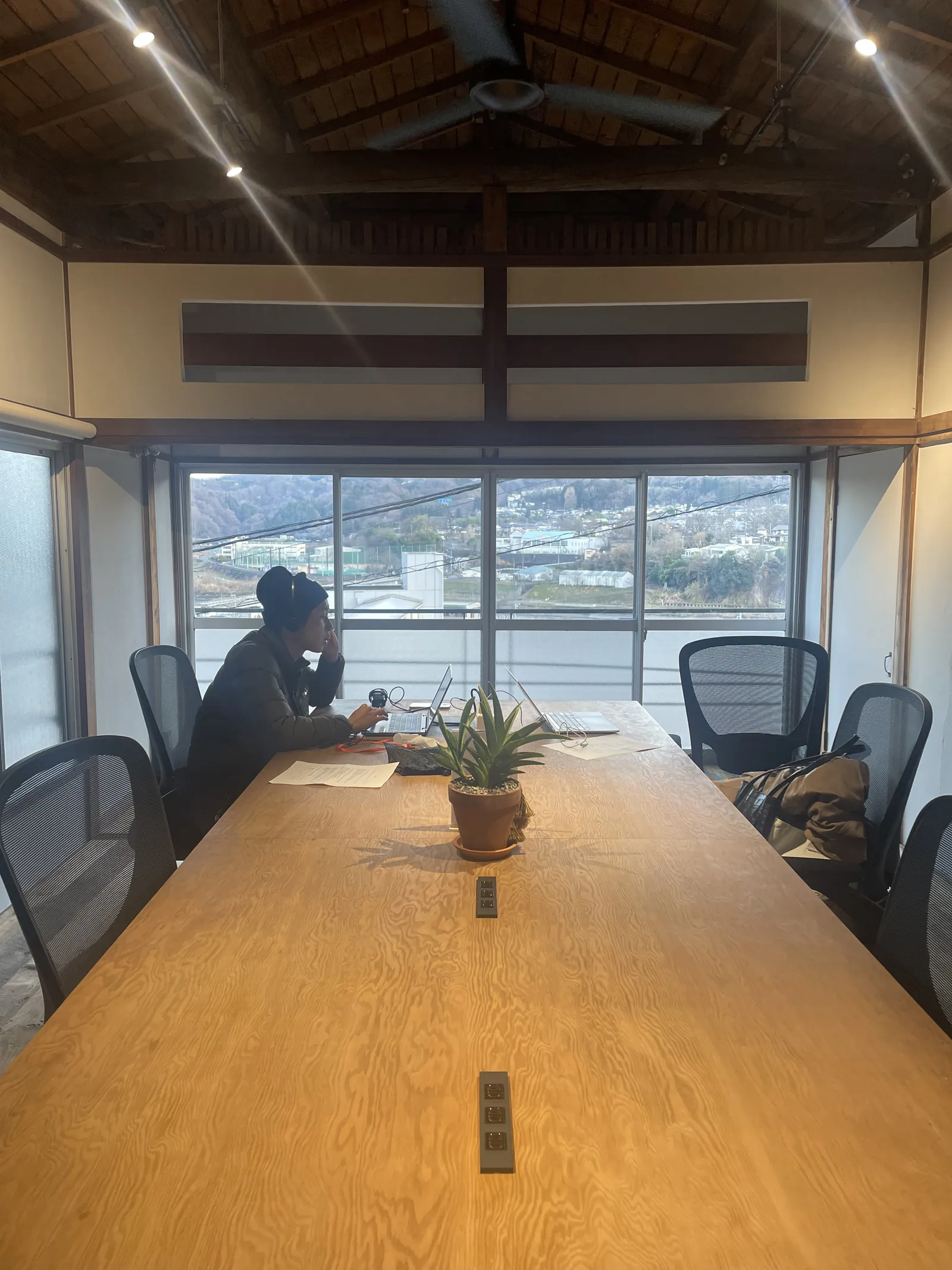 古民家の大きな机でPC作業をする井上